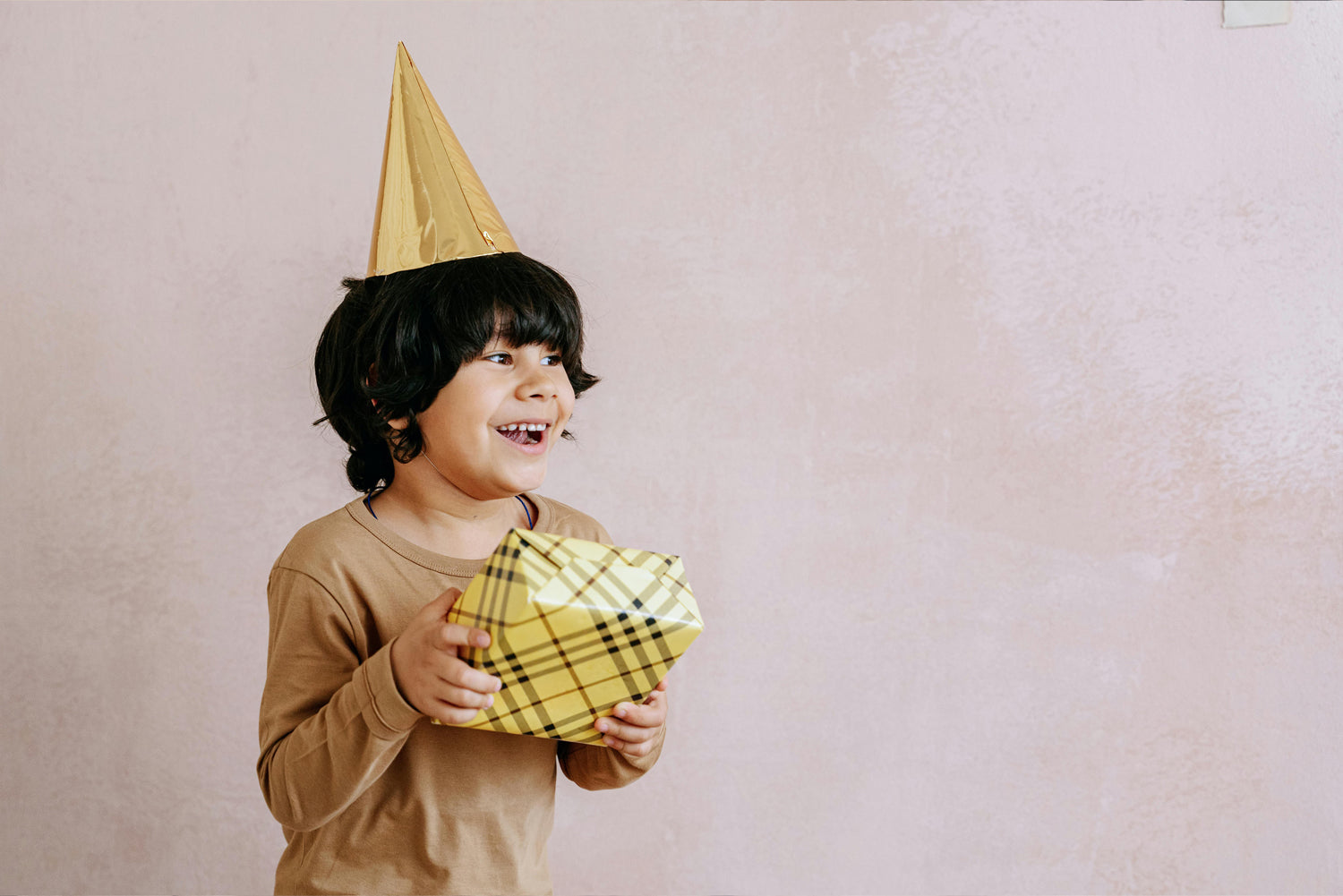 A child with birthday hat holding a wrapped personalized gift